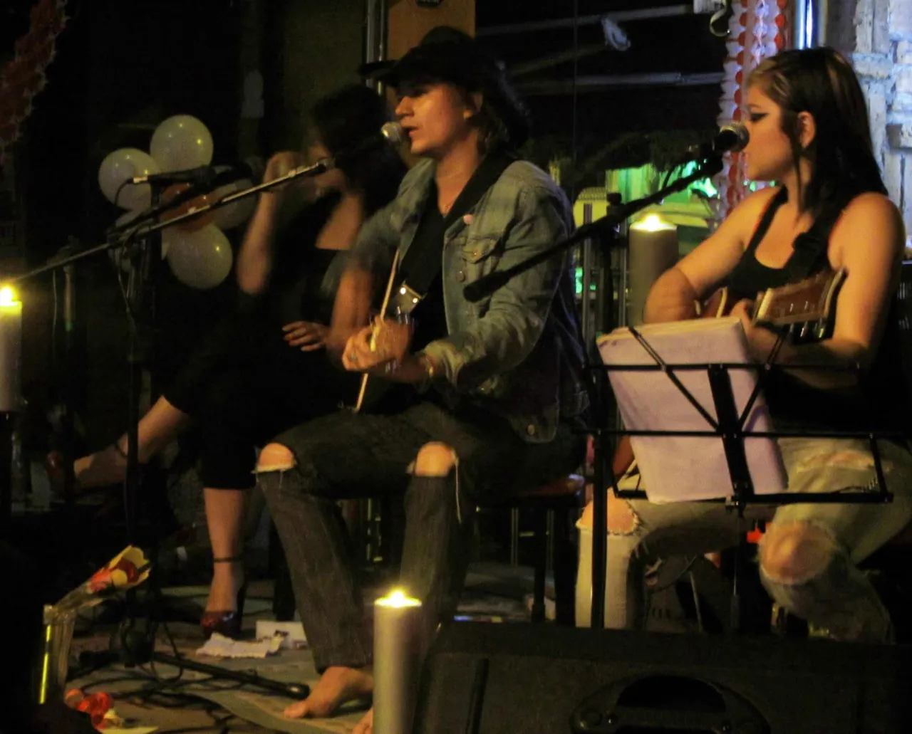 Mateo Acevedo cantando y tocando guitarra acústica junto a músicos invitados en un íntimo show acústico con velas.