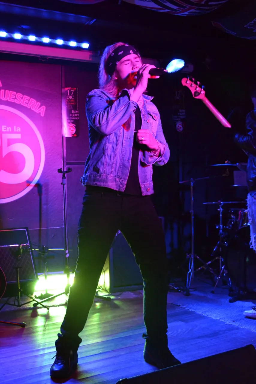 Mateo Acevedo cantando al micrófono en un escenario con luces de concierto