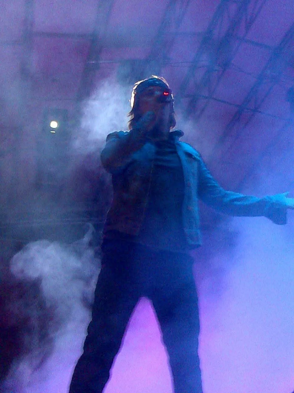 Mateo Acevedo en plena puesta en escena entre humo y luces azules durante un enérgico show de rock.