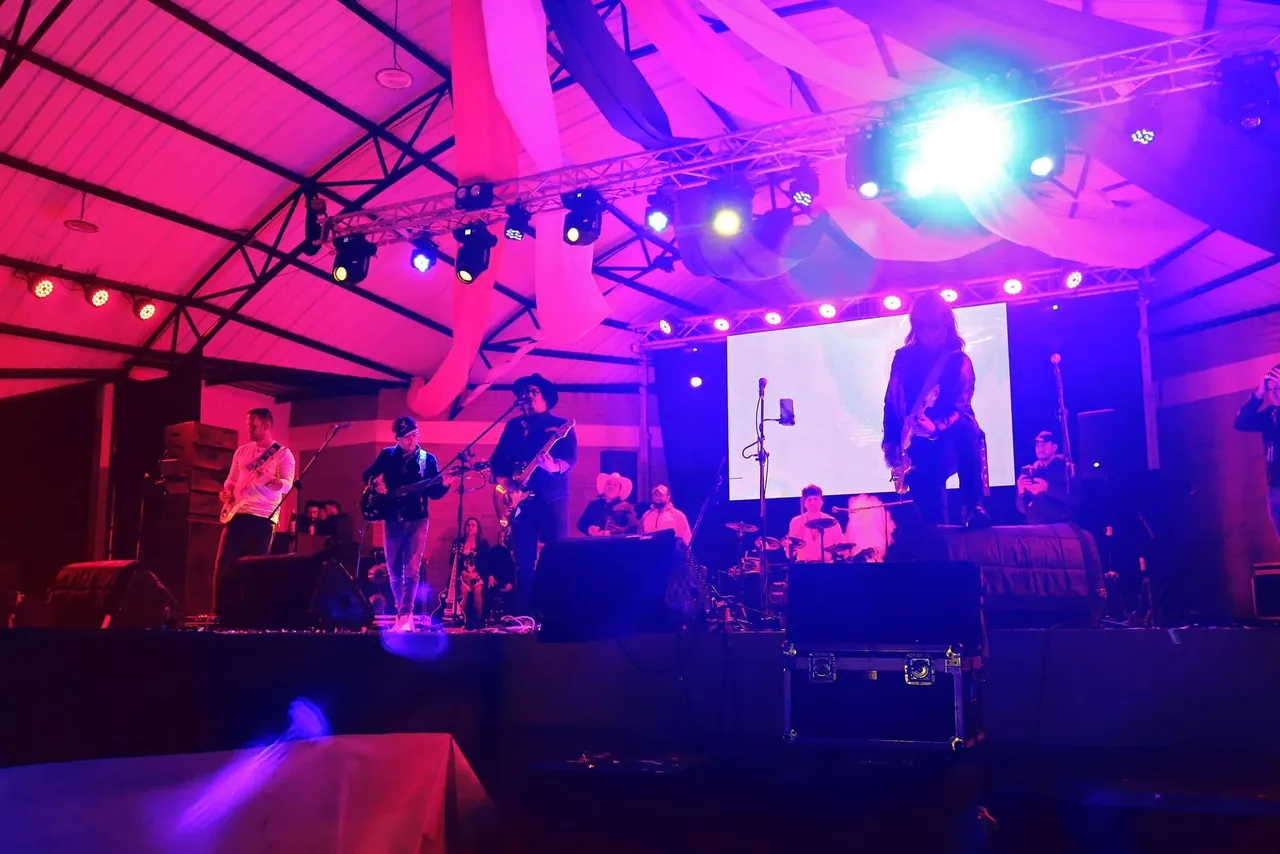 Mateo Acevedo y su banda en una tarima con iluminación púrpura durante un show en vivo.