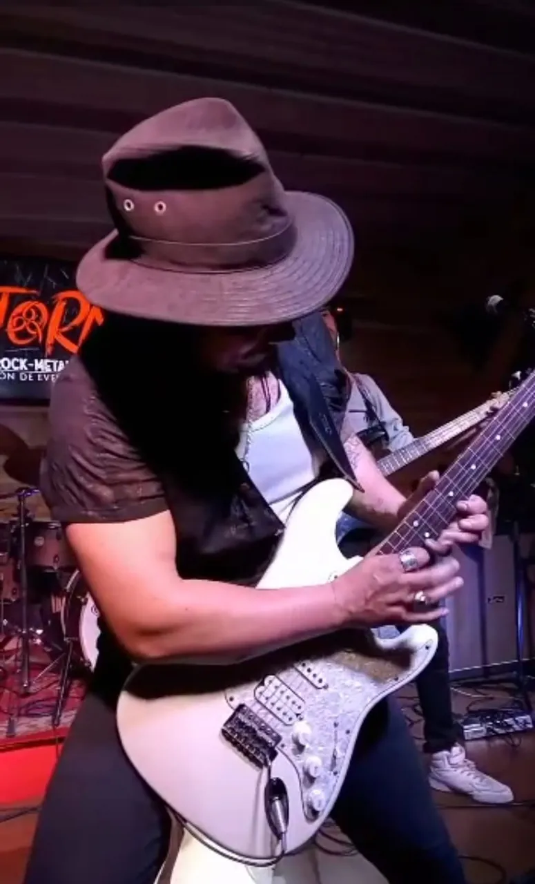 Mateo Acevedo concentrado en un solo de guitarra eléctrica durante una presentación de rock en vivo.
